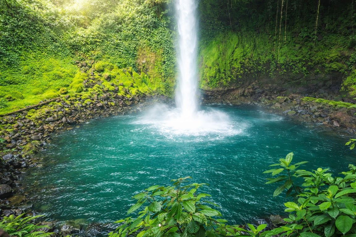 La Fortuna Waterfall with turquoise pool surrounded by lush rainforest, photographed during a guided tour with Arenal Volcano Costa Rica Tours.